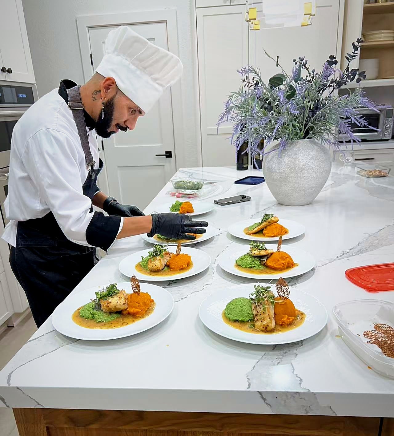 Plating seared fish with sweet potato and pea purée for a private dinner